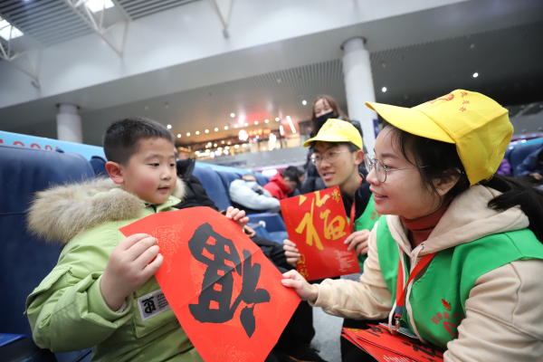 图三：1月10日，在南昌站候车厅，南昌工务段青年志愿者付映雪向旅客赠送春联。
