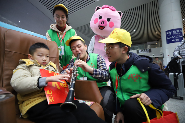 图一： 1月10日，在南昌站候车厅，南昌工务段青年志愿者方岳与小旅客互动，一同演奏乐曲。