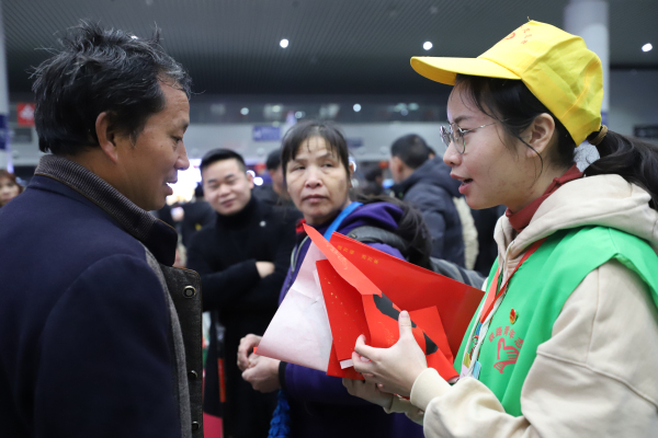 图四：1月10日，在南昌站候车厅，南昌工务段青年志愿者付映雪向旅客赠送春联。