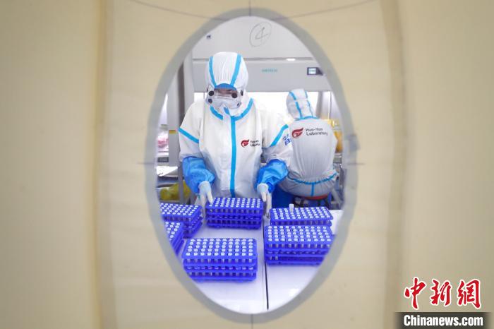 透过舱门窗户看到身穿防护服的工作人员忙碌的身影。　富田 摄