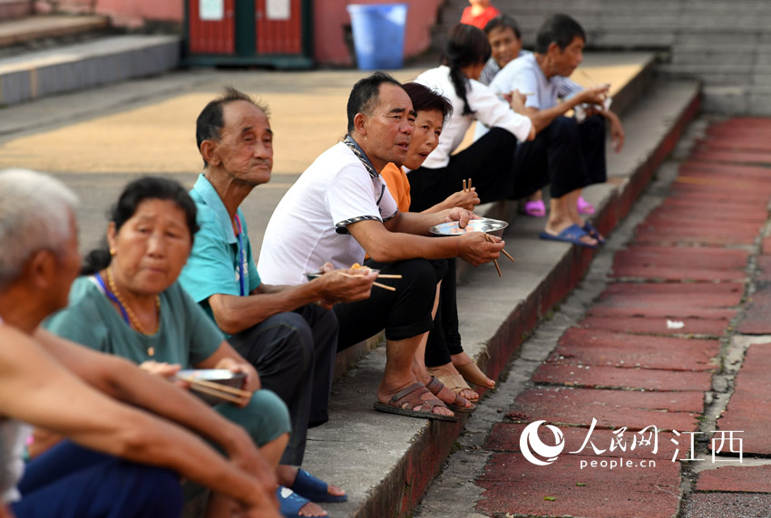 安置点的村民都是街坊邻居，不少人坐在台阶上边吃饭边聊天。（人民网 时雨/摄）