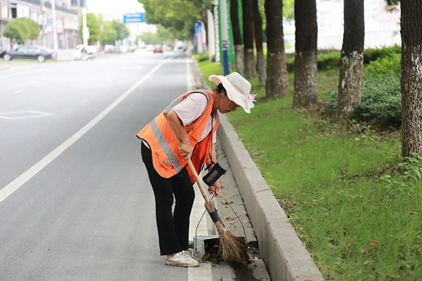 环卫工人田放春在清扫路边垃圾