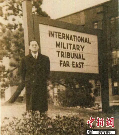 高文彬在远东国际军事法庭门口的木牌前。民盟上海市委会供图