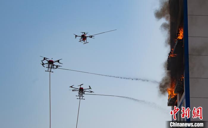 无人机通过携带消防水带、干粉挂载对火点施喷作业。　赵春亮 摄