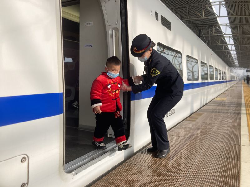 图为D6251次列车长董鑫琼正在牵扶小朋友下车