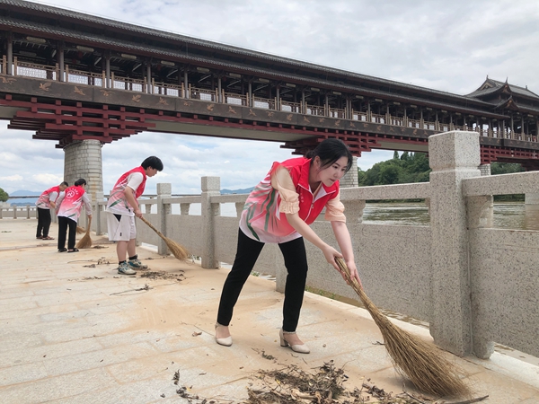 杨丽（右一）在赣江钟鼓楼社区河段清扫枯叶