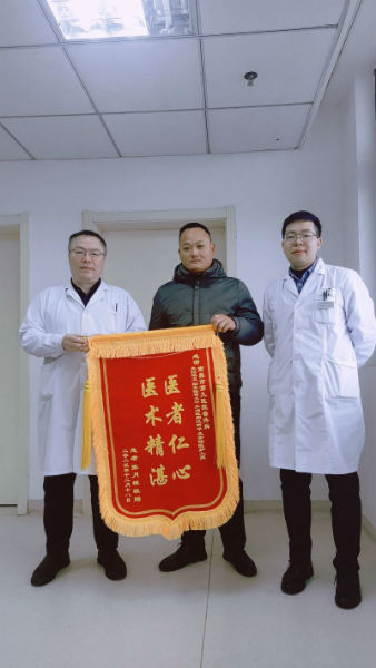 毛卫主任（右）接过患者家属送来的锦旗