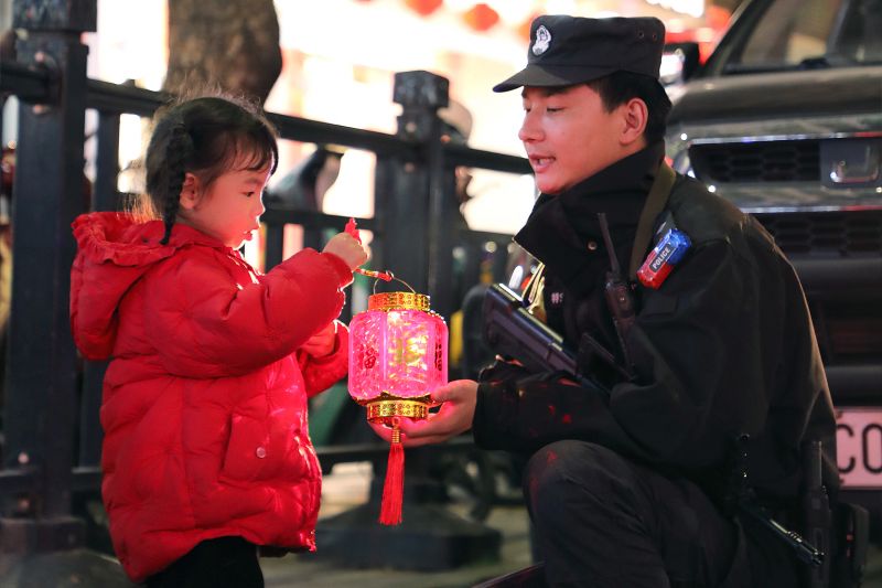 宜丰县新昌西大道，特巡警陪伴小朋友赏花灯。伍自丰 摄