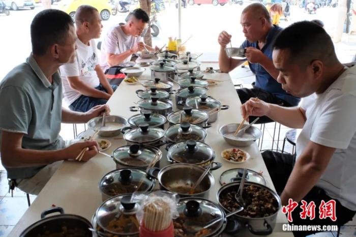 食客们正围坐在长桌前大快朵颐。刘俊聪 摄