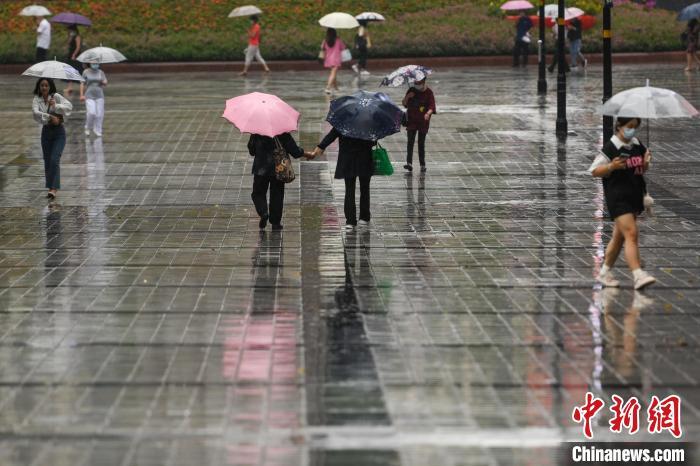 资料图：市民冒雨出行。　何蓬磊 摄