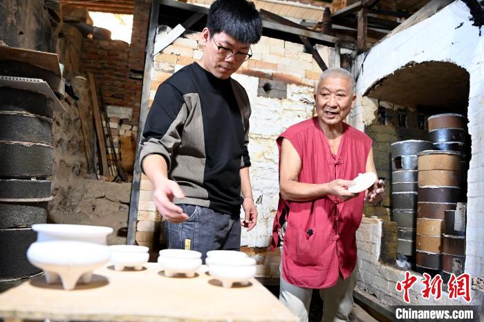 在窑口,林俊徒弟把已上釉的素坯传给师傅。 张金川 摄 在窑口,林俊徒弟把已上釉的素坯传给师傅。 张金川 摄