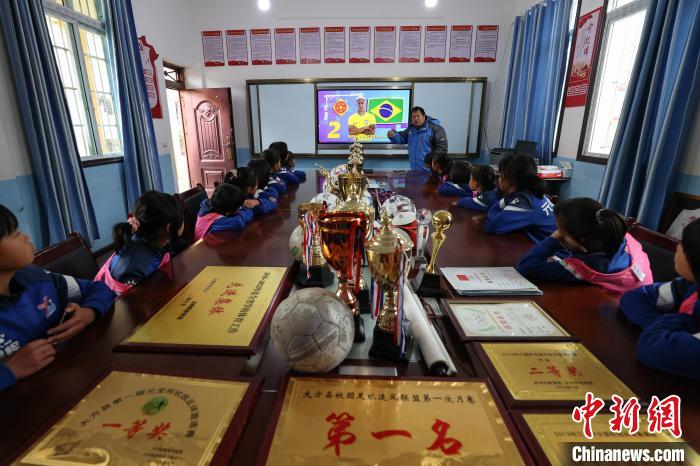 图为元宝女子足球队部分队员在观看战术视频，桌上摆满了元宝女足赢得的奖杯和奖牌。　瞿宏伦 摄