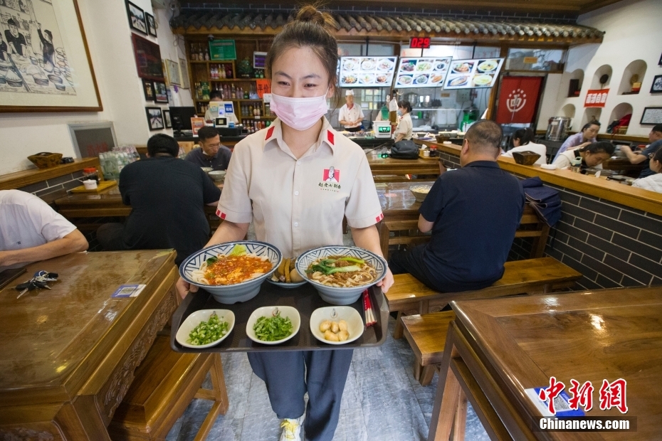 资料图为山西太原，赵老七削面馆的服务员为食客送上刀削面。 中新社记者 张云 摄