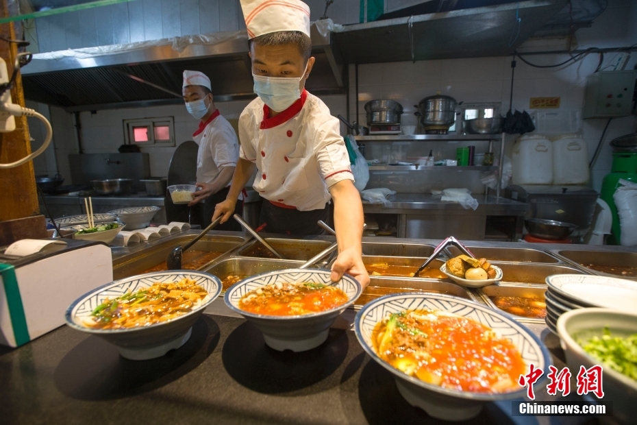 资料图为山西太原，赵老七削面馆的师傅在给刀削面浇卤汁。 中新社记者 张云 摄