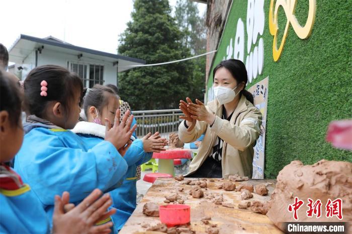 武胜县赛马镇第二幼儿园老师教孩子们做泥塑。　王林 摄