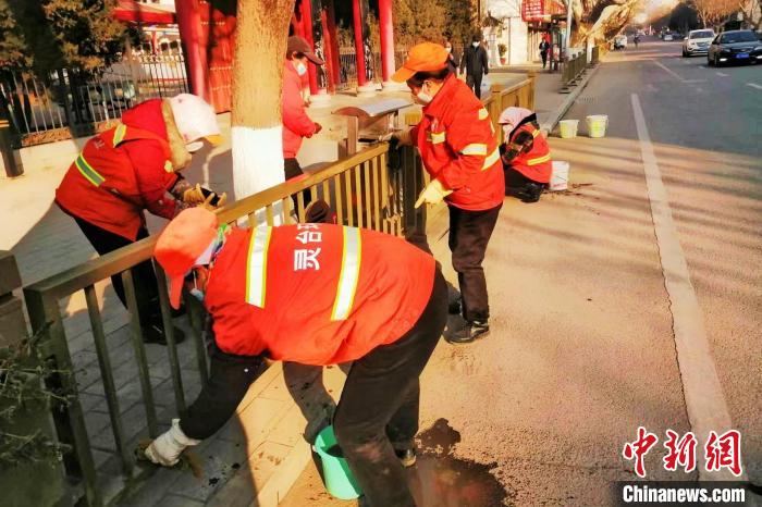 图为女环卫工清洁道路护栏。(资料图) 灵台县益源环境管理服务有限责任公司供图