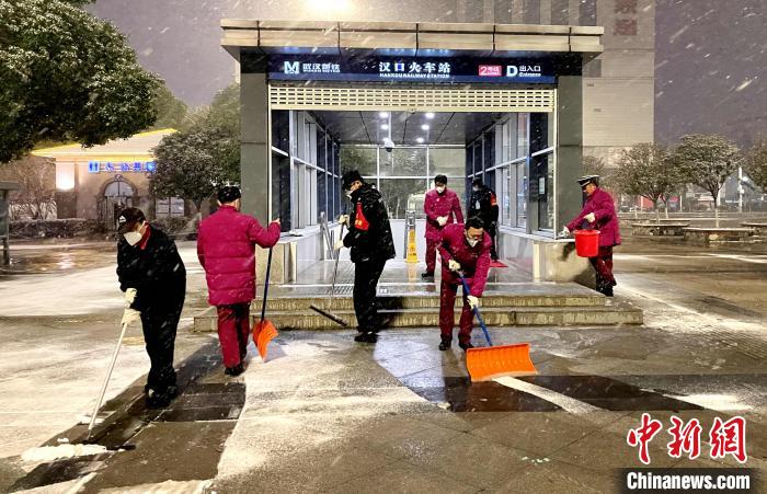 14日深夜，地铁工作人员清理出入口积雪 江曼 摄