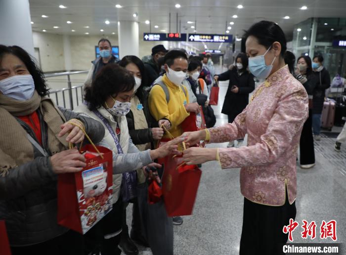 图为大连市文化和旅游局对外交流合作处二级调研员李守君向香港游客赠送小礼物。　杨毅 摄