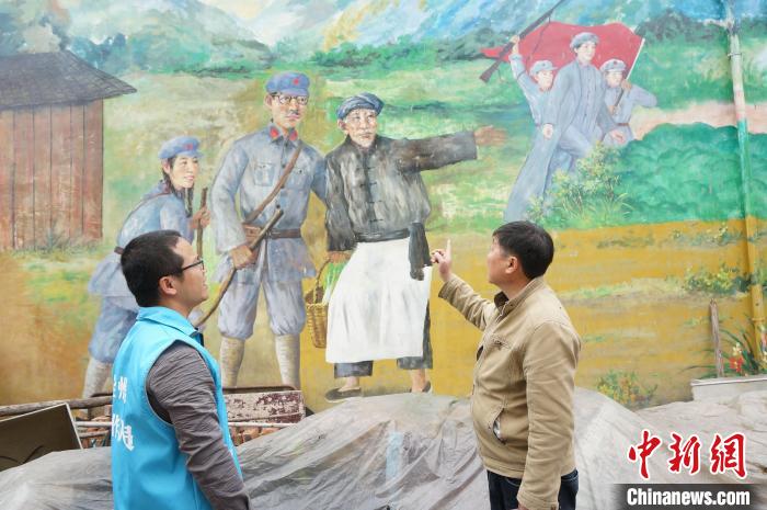 图为黄保持(左)与村干在一面大型主题墙绘前讨论有关红色文化项目建设的后续工作。　欧惠兰 摄