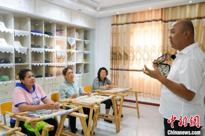 在哈密市伊州区陶家宫镇荞麦庄子村三队，卡德尔正在为绣娘讲解新一批订单的要求。　李瀚麒 摄