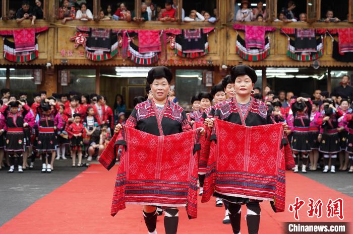 4月22日，在广西龙胜各族自治县龙脊镇黄洛瑶寨，当地瑶族民众在开展红瑶服饰T台走秀。　吴梦行 摄