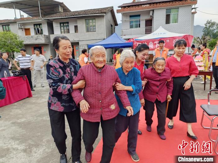 村民搀扶老人出席活动。　陈春花 摄