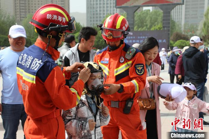 图为消防员带领小朋友体验佩戴空气呼吸器。　青海消防供图