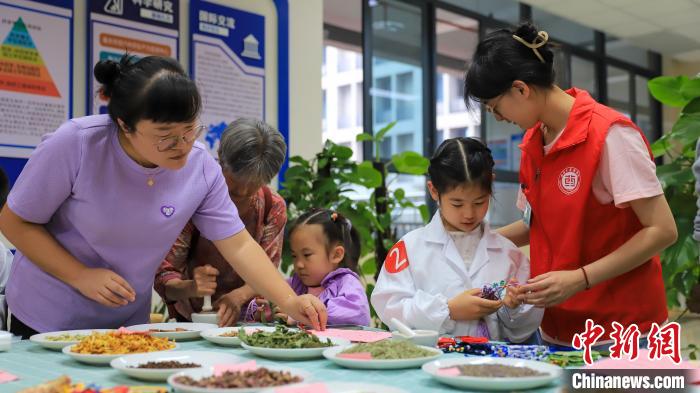 图为“小小药学家”在家长陪伴下制作香囊。　陈毅 摄