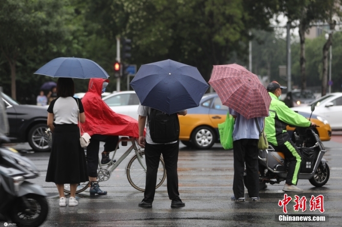 7月21日清晨，市民行走在雨中。7月20日夜间开始，北京雨水增多，7月21日是此轮降水主要影响时段，局地有暴雨，其中早上至中午伴有雷电、局地短时强降水等强对流天气，早晚高峰将受影响。北京市气象台已于20日15时发布暴雨蓝色预警信号。此外，随着雨水的到来，北京气温也将明显下降，高温天气有所缓解。图/ICphoto