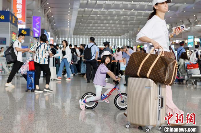 旅客带着孩子在铁路上海虹桥站候车大厅内行走。　殷立勤 摄