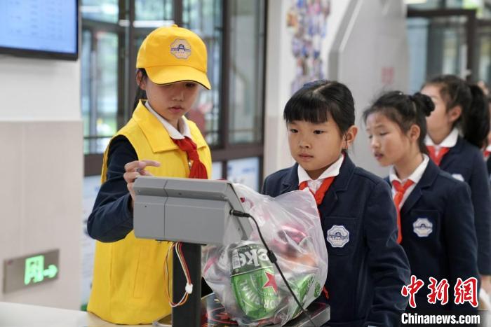 学生将家中的可回收物带到学校进行称重，用以兑换积分。　钱晨菲 摄