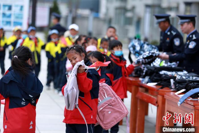 移民管理警察为学生发放书包，鼓励学生好好学习，将来成为栋梁之材。　肖富贵 摄