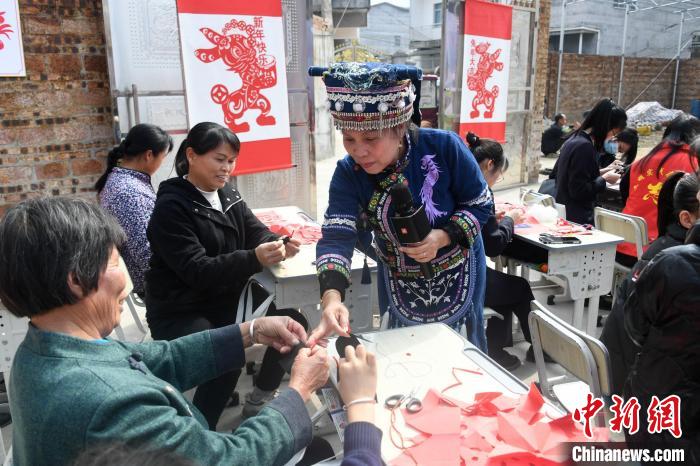 图为罗华清在指导村民学习剪纸技艺。　廖光福 摄