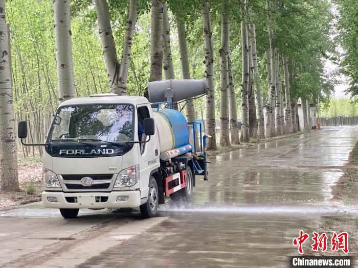 图为洒水车在对地面进行湿化，降低飘絮强度。　徐婧 摄