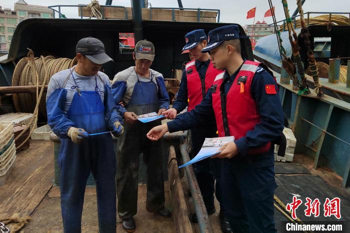 海警执法员给渔民分发伏季休渔宣传单。　福州海警局供图