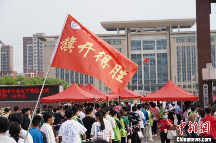 在菏泽市巨野县第一中学高考点，往届毕业生为考生摇旗助考。　臧东明 摄