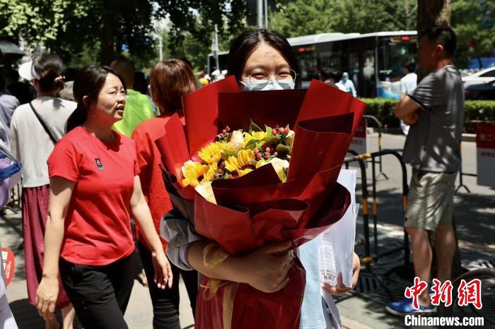 6月7日，中国人民大学附属中学考点，考生结束当日第一科语文考试后手捧鲜花走出考点。　中新社记者 易海菲 摄