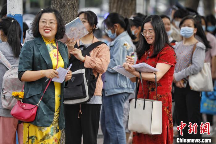 在山东泰安，带队老师身穿旗袍在泰安二中考点外为考生加油。　陈阳 摄