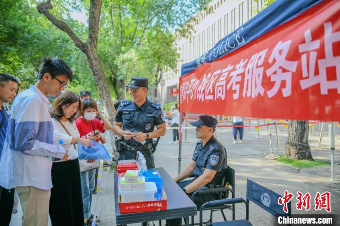 6月7日，天津，考生与家长在考场外天津特警设置的高考服务站领取保障物品。　佟郁 摄