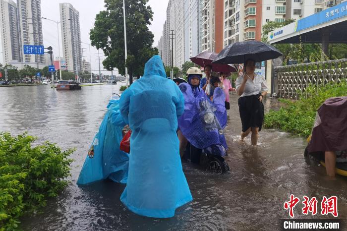 图为民众在积水路段通行。　翟李强 摄