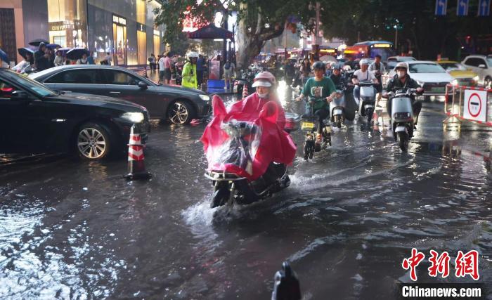 暴雨导致部分道路积水，市民骑车从水中驶过。　泱波 摄