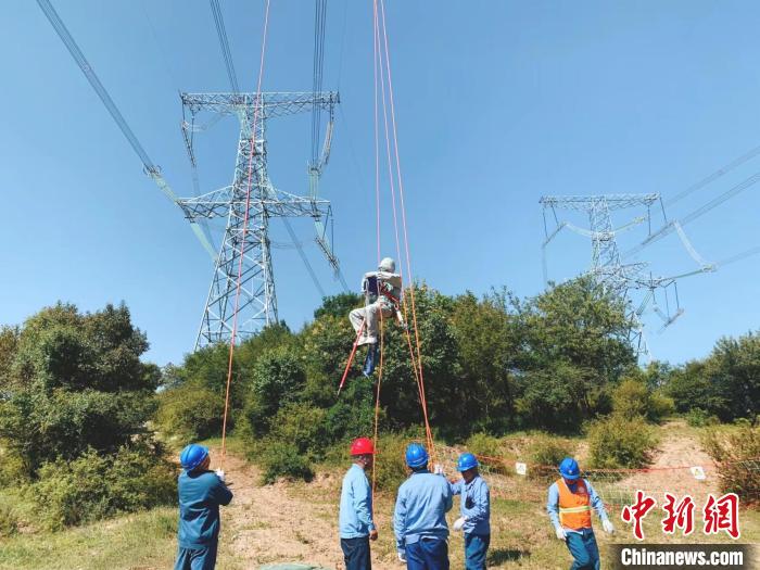 国网山西电力带电人员对某1000千伏线路铁塔进行带电作业。图为带电人员采用“小飞侠”进入等电位。　张江华 摄