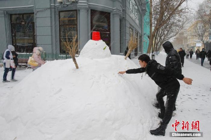 资料图：11月19日，黑龙江省哈尔滨市迎来大暴雪天气，虽给当地市民交通出行带来不便，但也营造了银装素裹的冬季美景。图为中央大街上的雪人吸引游客。 中新社记者 吕品 摄