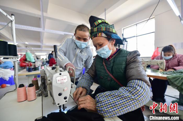 图为龙明贵( 左一)在服装加工车间指导工人加工服装。　杨武魁 摄