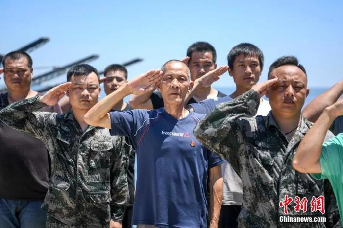 在洞庭湖一线防洪大堤大通湖防守堤段，一群退伍老兵坚守在岗位上，巡查排险并清理水葫芦，以保证大堤安全。8月1日是建军节，70岁的退伍老兵谭根云(中)和参与防汛的退伍老兵们一同敬军礼。杨华峰 摄