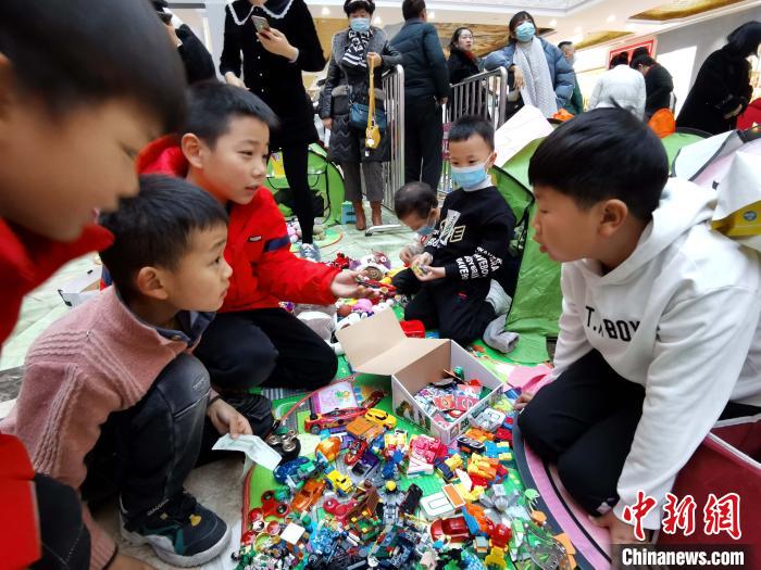 图为一位萌娃在跳蚤市场售卖自己的玩具。　张添福 摄