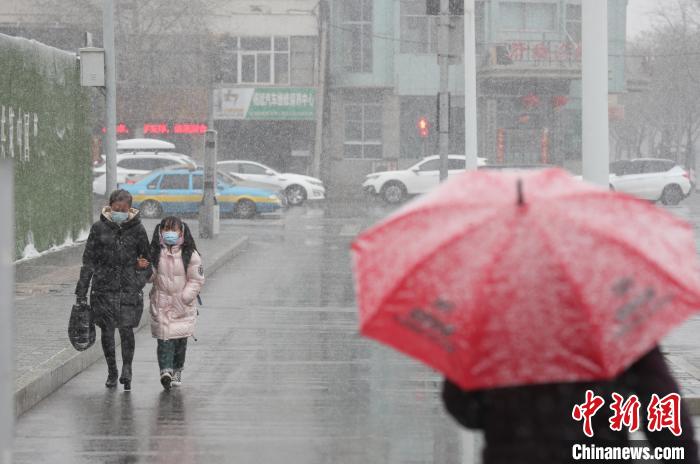 雨雪天里，市民撑伞出行。　于晶 摄