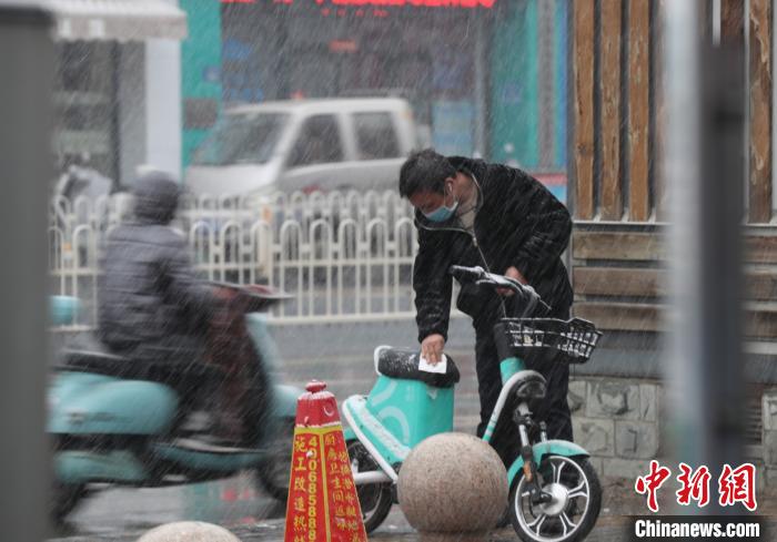 雨雪天里，出租车“紧俏”，市民骑共享单车出行。　于晶 摄