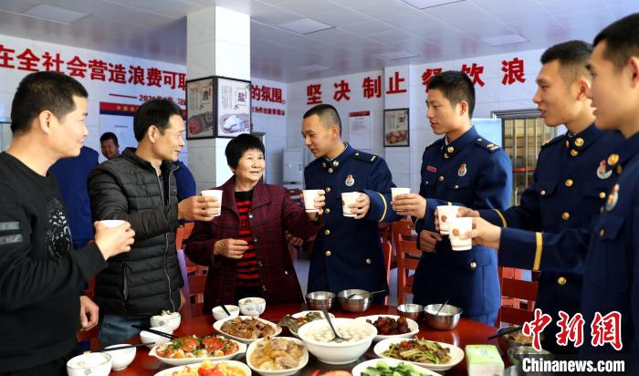 林奶奶与蓝田消防救援站指战员一同吃团圆饭，林奶奶举杯祝大家出警平安。　涂林发 摄