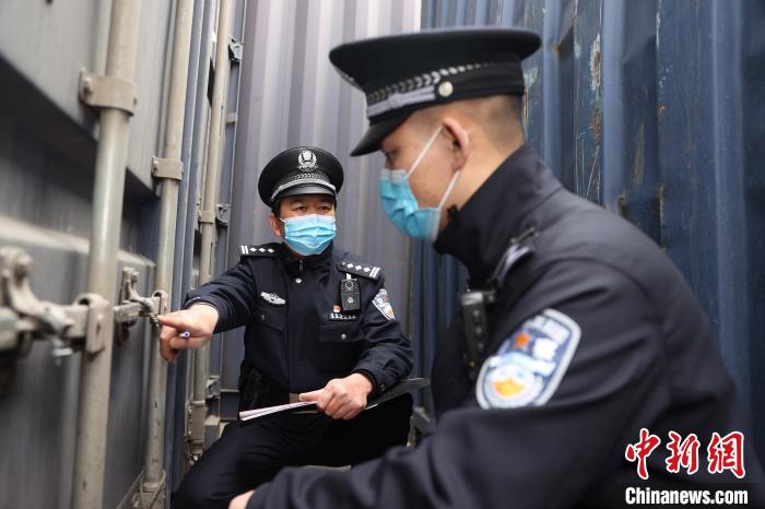 图为雷激(左)为同事传授中欧班列集装箱铅封痕迹经验。　胡勇 摄